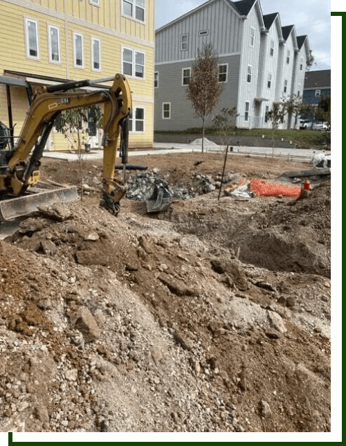 Excavator digging dirt near houses.