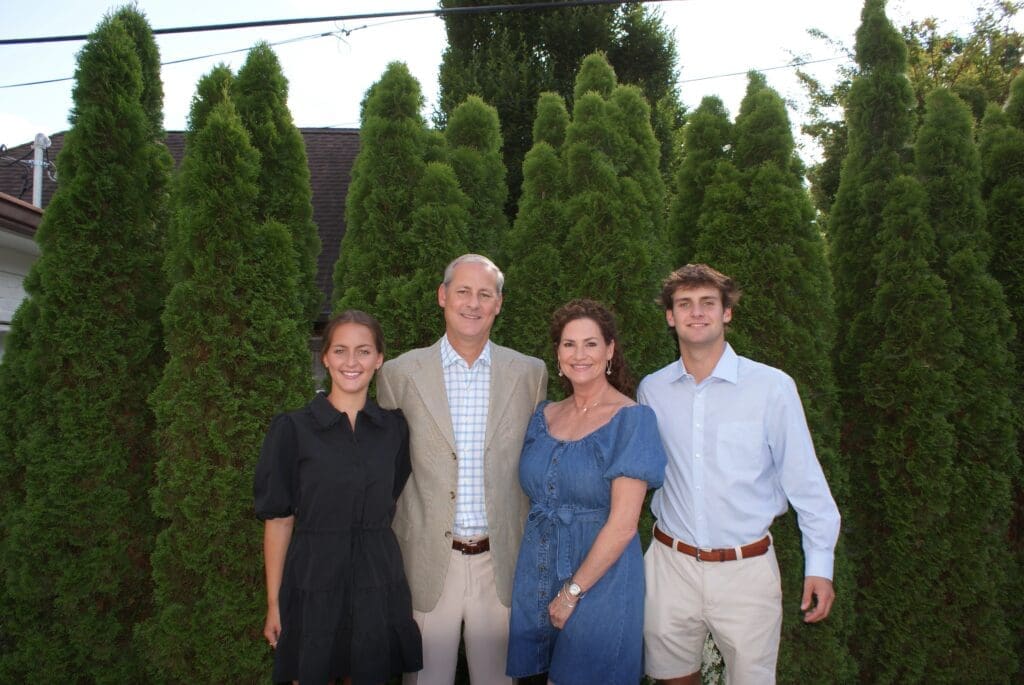 Family portrait in front of green bushes.